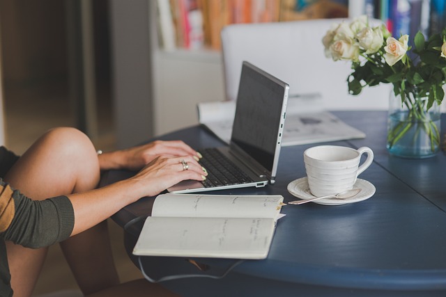 Lifestyle blogger balancing business and family at work desk with planner and laptop.