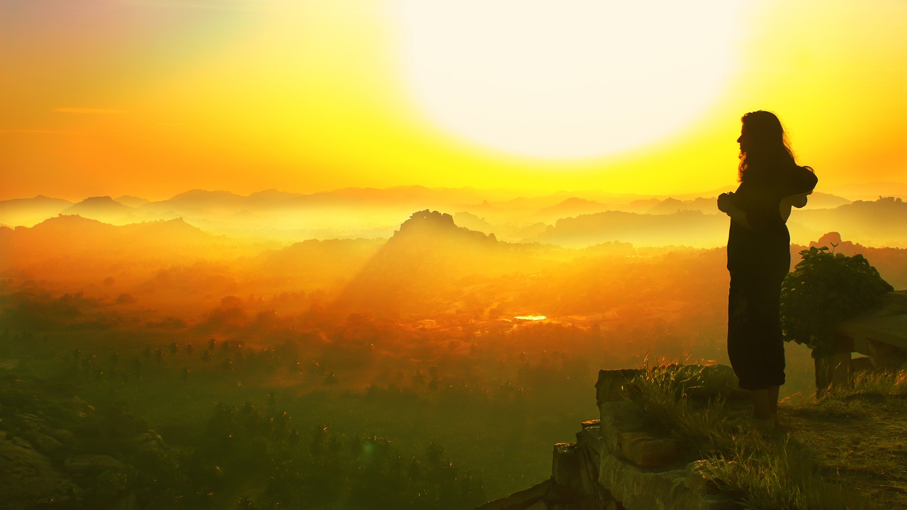 A person standing on a mountaintop at sunrise with, symbolizing self-belief and new beginnings.